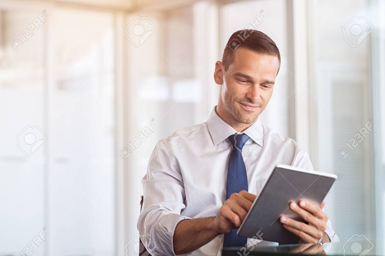 83142191 smiling businessman using digital tablet at work portrait of a happy formal man working on computer